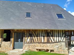 un bâtiment en pierre avec un toit gris et une porte dans l'établissement La Charretterie Cœur du village typique Normand, à Saint-Christophe-sur-Condé