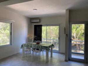 a dining room with a table and chairs and windows at Departamento Pinamar centro Jupiter in Pinamar