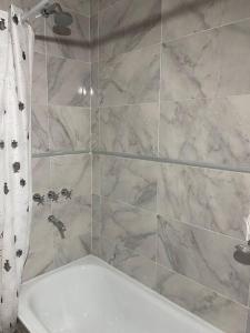 a bathroom with a marble shower curtain and a tub at Departamento Pinamar centro Jupiter in Pinamar +18 photos