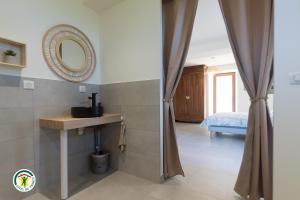 a bathroom with a mirror and a sink and a bed at Gîte des Mouliniers in Saint-Siméon-de-Bressieux