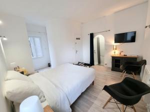 una camera con letto bianco e TV a parete di La Chambre Bleue - Chambre avec salle de bain ad Argenton-sur-Creuse