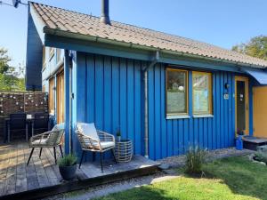 ein blaues Haus mit zwei Stühlen auf einer Terrasse in der Unterkunft Ferienhaus "Auszeit mit Herz" im Ferienpark Extertal - Kamin, Fass-Sauna, Massagesessel in Extertal