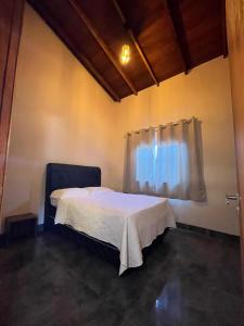 a bedroom with a white bed with a window at Casa Veiga in Pirenópolis +4 photos