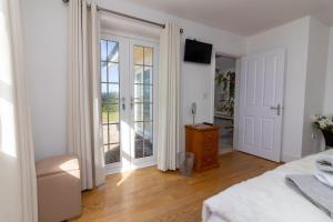 a white bedroom with a bed and a sliding glass door at Sheerghlass in Castletown