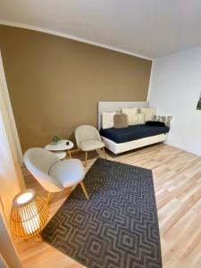 a room with a bed and two chairs and a rug at SLEEP WELL Apartments DETMOLD - Tempur Beds- NEU - Top Lage - Free parking - WIFI in Detmold
