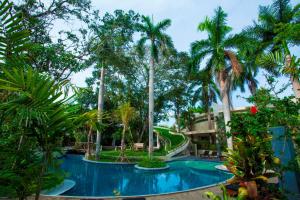 a resort with a swimming pool with palm trees at Regali Villa Canggu in Canggu