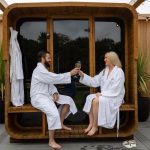 un hombre y una mujer sentados en un banco con una copa de vino en The Club Hotel at Goffs, en Naas