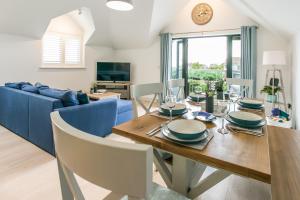 a dining room with a table and a blue couch at Seashells Bracklesham Bay in Chichester