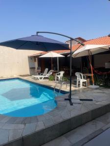 a swimming pool with chairs and umbrellas next to a house at Casa no Centro de Pirenópolis in Pirenópolis