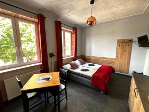 a bedroom with a bed and a table and windows at Apartamenty Rycerskie in Inowłódz