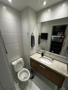 a bathroom with a toilet and a sink and a mirror at Lindo Flat1 Moderno AR Bela Vista Volta Redonda in Volta Redonda