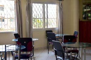 um quarto com mesas, cadeiras e janelas em Hotel Top Five em Kampala