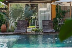 two chairs and an umbrella next to a swimming pool at Casa Paula in Barra Grande