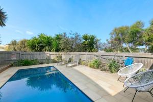 a swimming pool with chairs and a fence at Coastal Escape on Highlander in Torquay