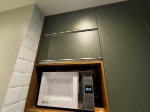 a microwave oven in a shelf with a mirror at Lindo Flat1 Moderno AR Bela Vista Volta Redonda in Volta Redonda