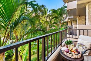 Un balcón con palmeras y una canasta de comida. en Paki Maui 313, en Kahana