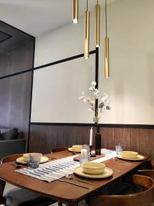 a dining room table with yellow plates and flowers on it at K Avenue Kota Kinabalu in Donggongon
