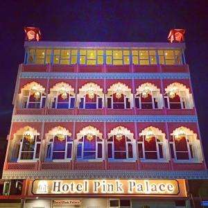 un palacio rosa de hotel se ilumina por la noche en Hotel Pink Palace, en Jaipur