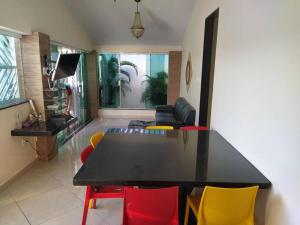 a living room with a black table and colorful chairs at Casa de Veraneio BiaBiel in Aracaju
