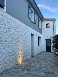 eine Steinmauer neben einem weißen Gebäude in der Unterkunft L'Oasis, Appartement Confort, Centre-ville in La Tremblade