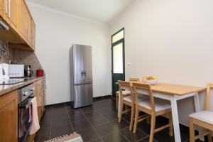 een keuken met een tafel en een roestvrijstalen koelkast bij Casa da Jackie in Funchal +17 foto's