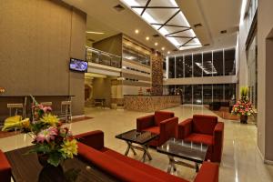 a lobby with red chairs and a table in a building at Hotel Dafam Pekanbaru in Pekanbaru