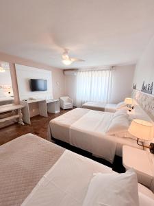 a bedroom with three beds and a flat screen tv at Pousada Betânia in Gramado