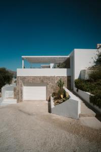 a white house with a garage on a driveway at Villa Sávra in Plakias