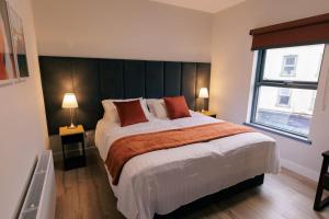 een slaapkamer met een groot bed en een raam bij River Walk Apartments in Derry Londonderry