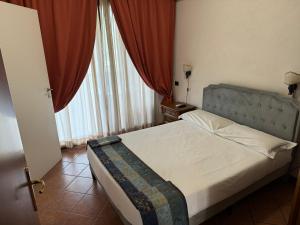 a bedroom with a bed and a window with red curtains at EURO HOUSE INN airport in Fiumicino