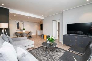 a living room with a couch and a tv at 16 on Bree Modern 2BR Luxury Apartment in Cape Town