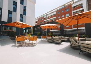 eine Terrasse mit Tischen, Stühlen und Sonnenschirmen in der Unterkunft Vibe Stay Granada in Granada