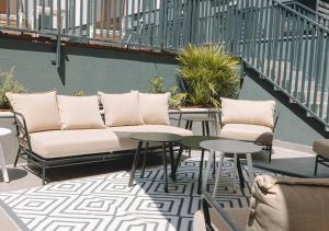 eine Couch auf einer Terrasse mit Tischen und Stühlen in der Unterkunft Vibe Stay Granada in Granada