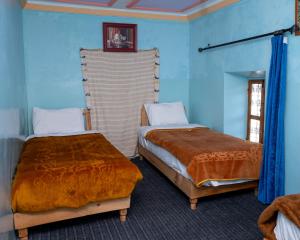 duas camas em um quarto com paredes azuis em Gite Tamounte em Tabant