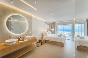 a bathroom with two beds and a sink and a mirror at Blue Haven - Ocean View Penthouse with private jacuzzi and community pool in Acantilado de los Gigantes