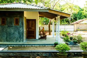 una casa con porche y una mujer sentada en una silla en Sunshadow Chalet, en Tangalle