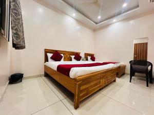 una camera da letto con un grande letto in legno con cuscini rossi di Hotel Hare Krishna Dham a Vrindāvan