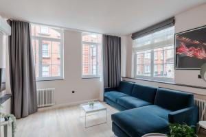 - un salon avec un canapé bleu et 2 fenêtres dans l'établissement Soho Swank - by Frankie Says, à Londres
