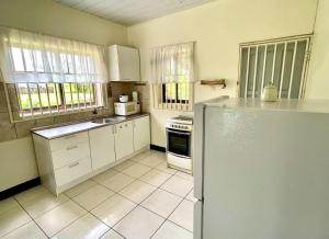 a kitchen with white cabinets and a refrigerator at 3 Bed House - Sleeps 6 - Garden - Parking - Wifi in Paramaribo