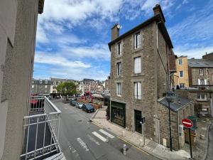 ein altes Backsteingebäude in einer Stadtstraße mit Autos in der Unterkunft Appartement entre plage de l'Ecluse et place du marché in Dinard