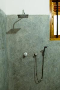 a shower with a hose attached to a wall at Sunshadow Chalet in Tangalle