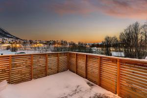 a snow covered balcony with a wooden fence at Arctic Aurora Apartment I SAUNA I Family & Groups in Tromsø
