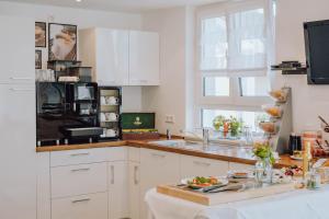 a kitchen with white cabinets and a sink and a window at Pension Sterntaler in Rheinhausen