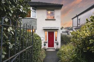 una porta rossa su una casa bianca con una recinzione di Ellerthwaite Place X3 Bed House with Hot Tub in Central Windermere a Windermere
