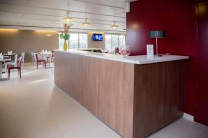 eine Bar in einem Restaurant mit roten Wänden und Tischen in der Unterkunft Hôtel Inn Design Laval in Laval