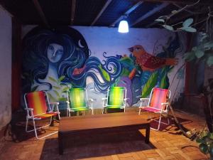 a room with chairs and a wall with a mural at Maloca Hospedagem in Sao Jorge