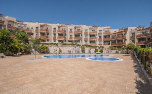 a large apartment complex with a swimming pool in a courtyard at Luxury Apartament Calle Pizarro La Tejita in La Mareta