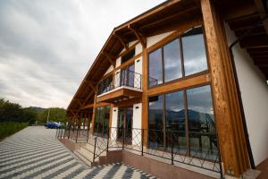ein Haus mit Glasfenstern und einem Balkon in der Unterkunft Pensiunea Subcarpati in Jiblea Veche
