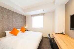 a bedroom with a bed with orange pillows and a television at Tokyu Stay Gotanda in Tokyo