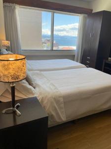 une chambre avec un lit avec une lampe et une fenêtre dans l'établissement Costa Nahuel Apartments 1, à San Carlos de Bariloche